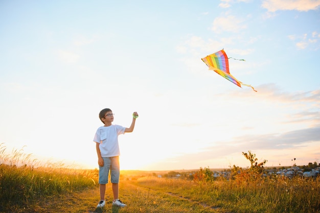 Children launch a kite in the field at sunset