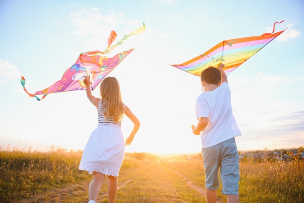 Children launch a kite in the field at sunset