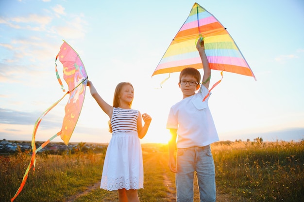 Children launch a kite in the field at sunset