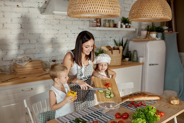 Children learn how to prepare a salad in the kitchen. Family day off, lunch with your own hands. Mom and young cooks