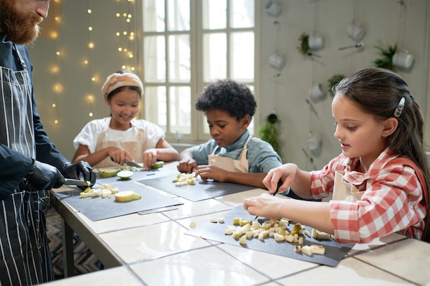 Children learning to cu fruits with the chef