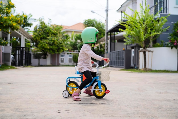 自転車に乗る少女の外の私道で自転車を運転することを学ぶ子供たち