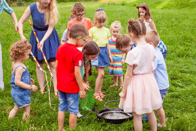 夏の公園で大きなシャボン玉を作ることを学ぶ子供たち