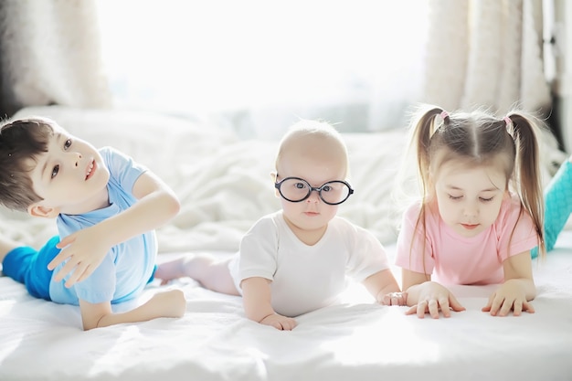 Children lie on the bed next to the newborn baby, little sister. Children's emotions.