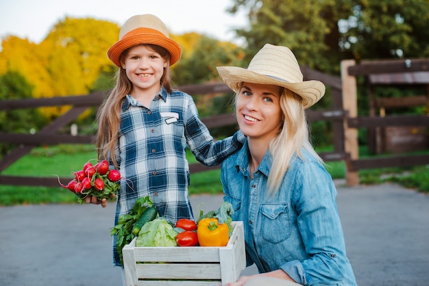 Mamma della tenuta della bambina dei bambini un canestro delle verdure organiche fresche con il giardino domestico.