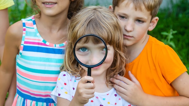 Children look at a magnifying glass on the nature. Selective focus. Nature.