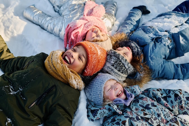 Foto bambini sdraiati sulla neve e che ridono