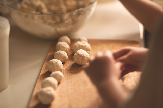 Children making a cottage cheese balls Russian syrniki in the home kitchen.