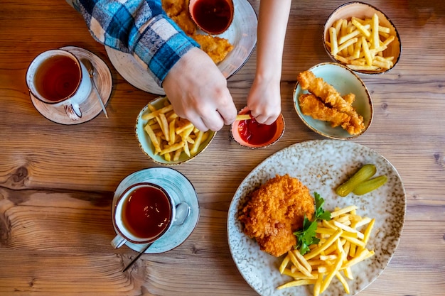 Children and man hands Picking French Fries on wood table in restaurant