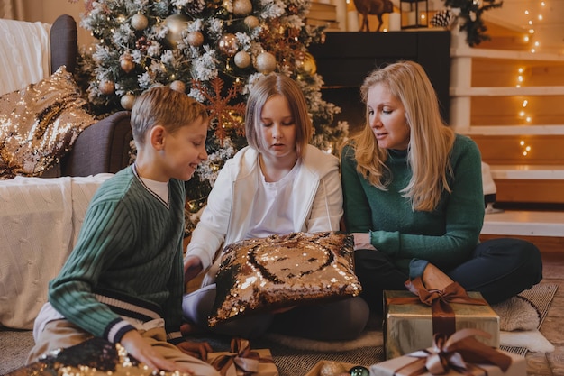 I bambini e la madre stanno decorando l'albero di natale, buon natale e le vacanze di capodanno. famiglia, vacanze invernali e concetto di persone, famiglia amante del ritratto da vicino.