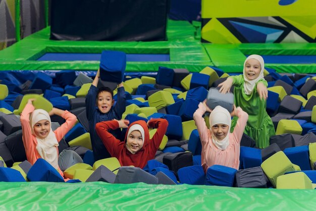 Photo children in muslim clothes jumping in soft cubes