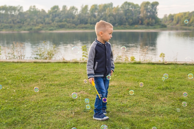 Children and nature concept. Boy trying to catch soap bubbles