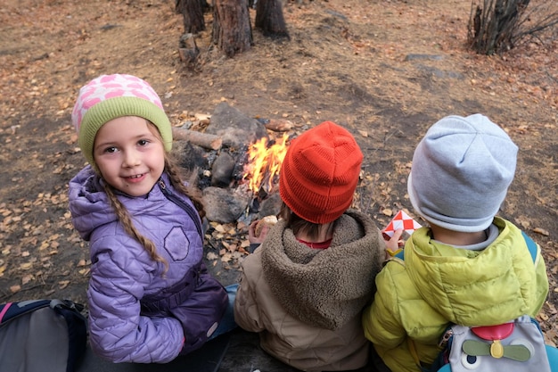 Bambini vicino al falò nei boschi autunnali durante il campeggio