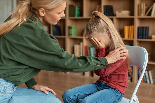 Children need help little girl crying in psychologist39s office\
professional female psychotherapist comforting kid