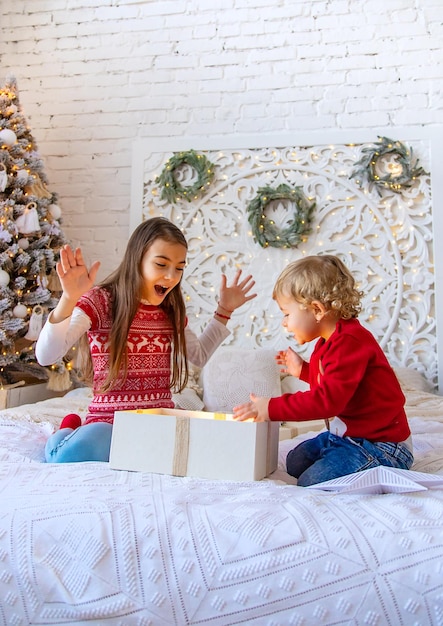 I bambini aprono i regali di natale sotto l'albero fuoco selettivo