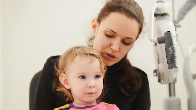 Photo children ophthalmology  mother and cute little girl  optometrist checks childs eye