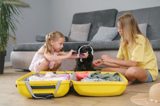 Photo children packing suitcase for travel and play with a dog in headphones