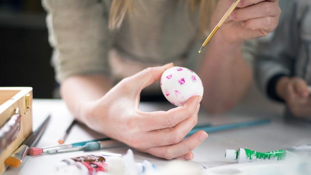 children paint easter eggs on a table with art materials