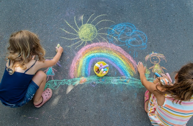 Children paint a rainbow on the asphalt. Selective focus. Kids.