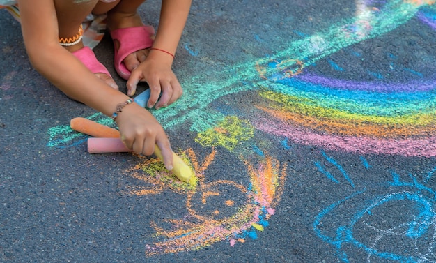 Children paint a rainbow on the asphalt. Selective focus. Kids.