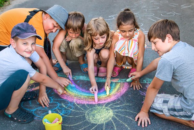 Children paint a rainbow on the asphalt. Selective focus. Kids.