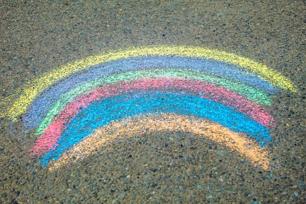 Children paint a rainbow on the asphalt selective focus