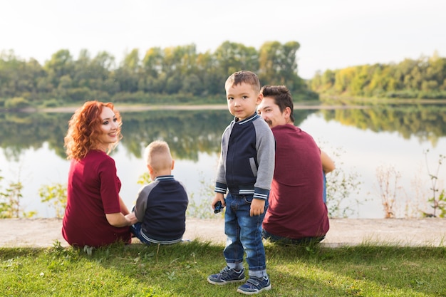 Концепция детей, отцовства и природы - большая семья, сидя на траве