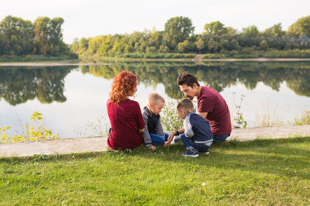 Foto concetto di bambini, genitorialità e natura - grande famiglia seduta sull'erba