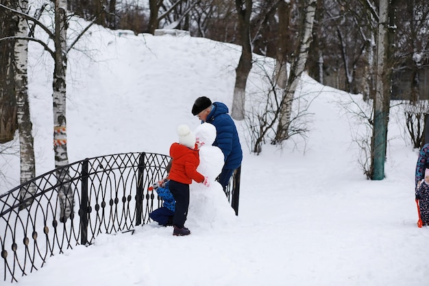 冬の公園の子供たち。子供たちは遊び場で雪で遊ぶ。彼らは雪だるまを彫刻し、丘を滑り降ります。