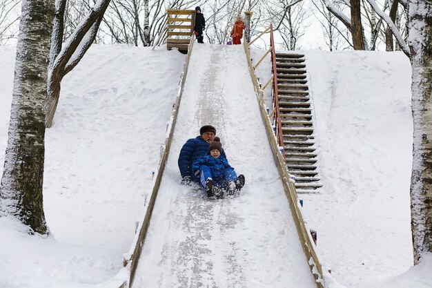 冬の公園の子供たち。子供たちは遊び場で雪で遊ぶ。彼らは雪だるまを彫刻し、丘を滑り降ります。