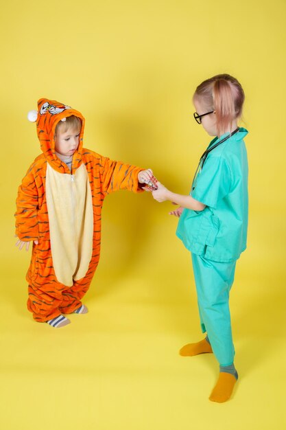 Photo children play doctor, a girl in a doctor's costume passes the medicine to a boy in a tiger costume