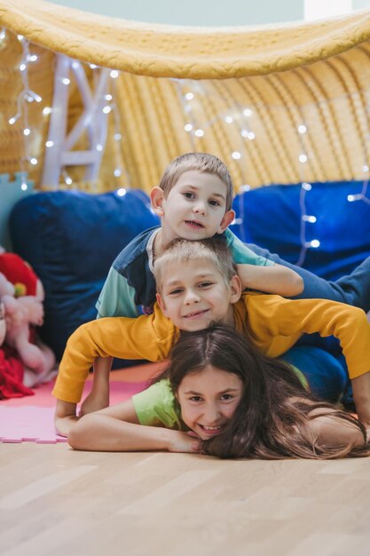 Foto i bambini giocano a casa con i cuscini e la coperta coperta nella sala giochi