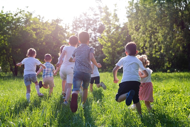 Children play outdoors running and having fun on a grass field