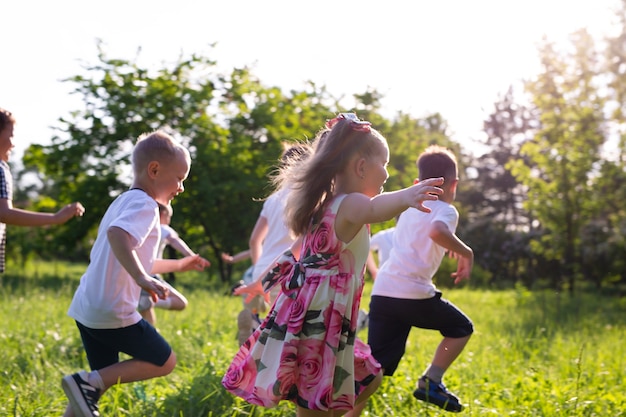 Children play outdoors running and having fun on a grass field