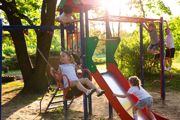 Children play outdoors running and having fun on a park with nature around