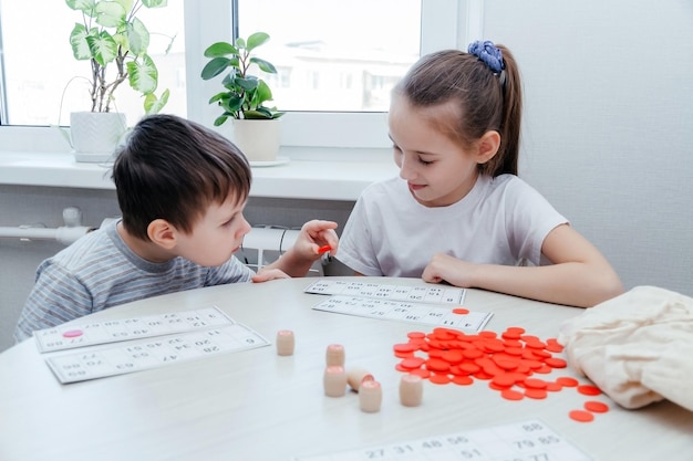 Children play Russian lotto on the table A girl and a boy play a board game Barrels with numbers