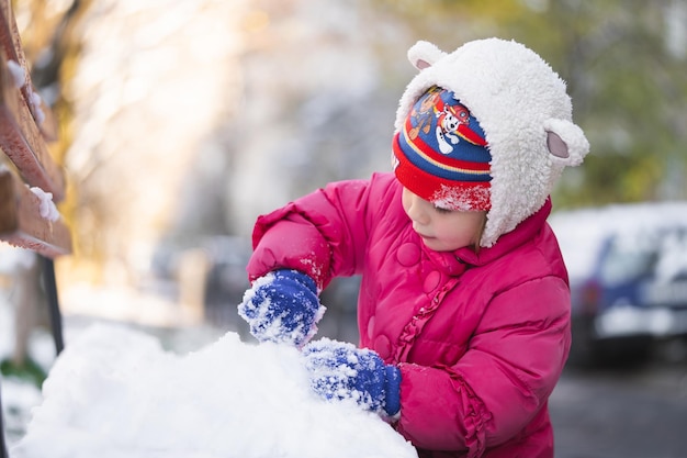 Children play in snowballs in winter dressed in warm jackets