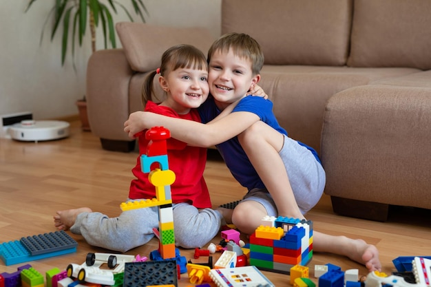 子供たちは床にコンストラクターを持ってカラフルなおもちゃで遊んで抱きしめます