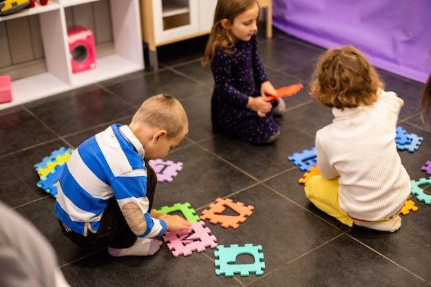 I bambini giocano insieme con lettere e puzzle all'asilo nido