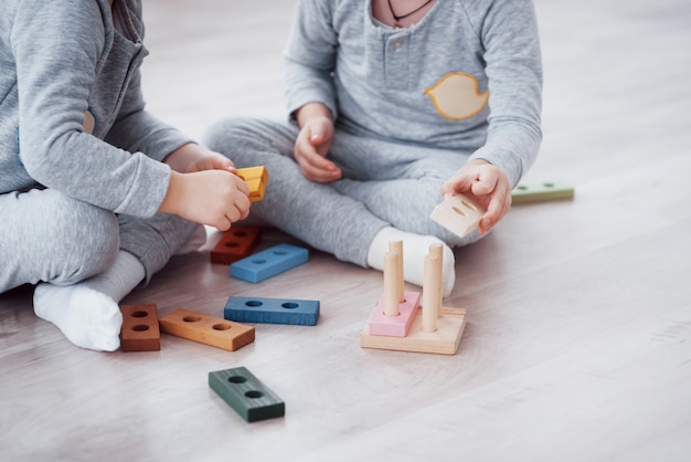 Children play with a toy designer on the floor of the children's room. 