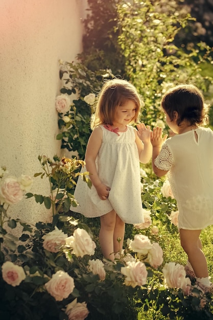 Children playing patty cake in summer garden on sunny day