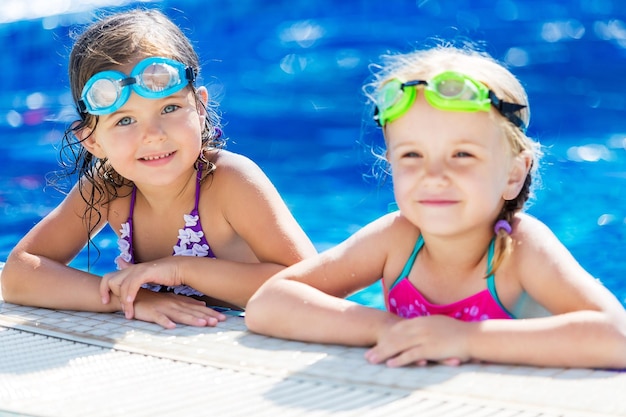 Дети играют в бассейне. Две маленькие девочки веселятся в бассейне.
