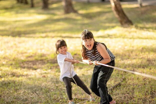 Photo children playing tug of war at the park on sunsut