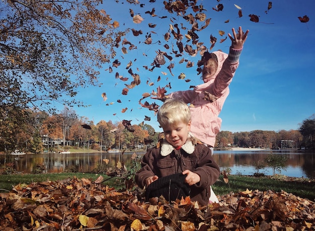 Photo children playing with autumn leaves at park