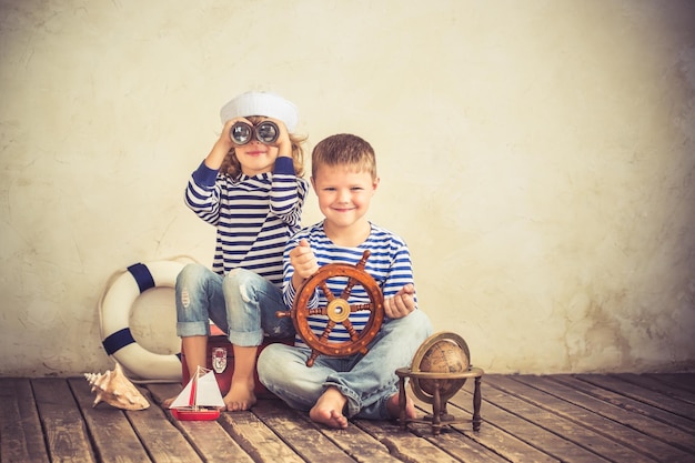 Children playing with vintage nautical things Kids having fun at home Travel and adventure concept Retro toned image