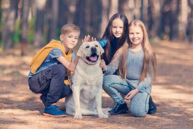 Children pose with a white dabrador Walking the dog