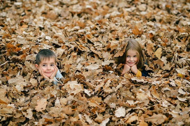 Children posing in autumn leaves