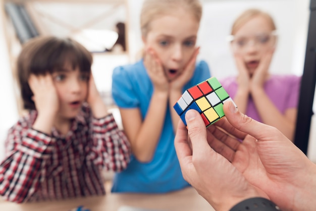 Foto i bambini stampano oggetti diversi sulla stampante 3d con un insegnante.