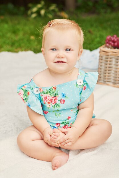 Children protection day, baby girl in the park sits in a basket on a summer picnic