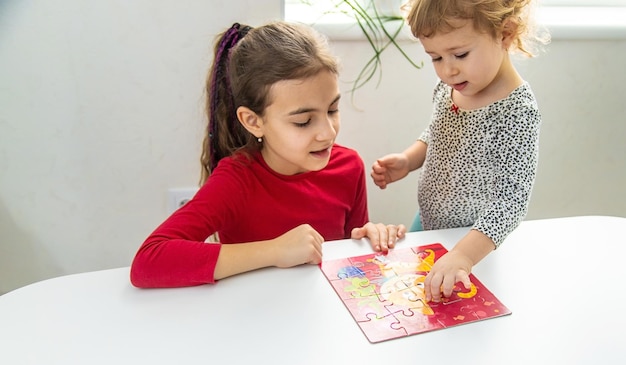 I bambini mettono insieme un puzzle sul tavolo fuoco selettivo